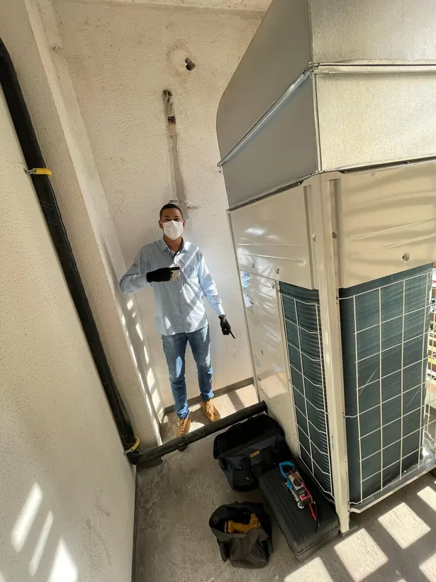Técnico ao lado de condensadora de grande porte instalada em área técnica