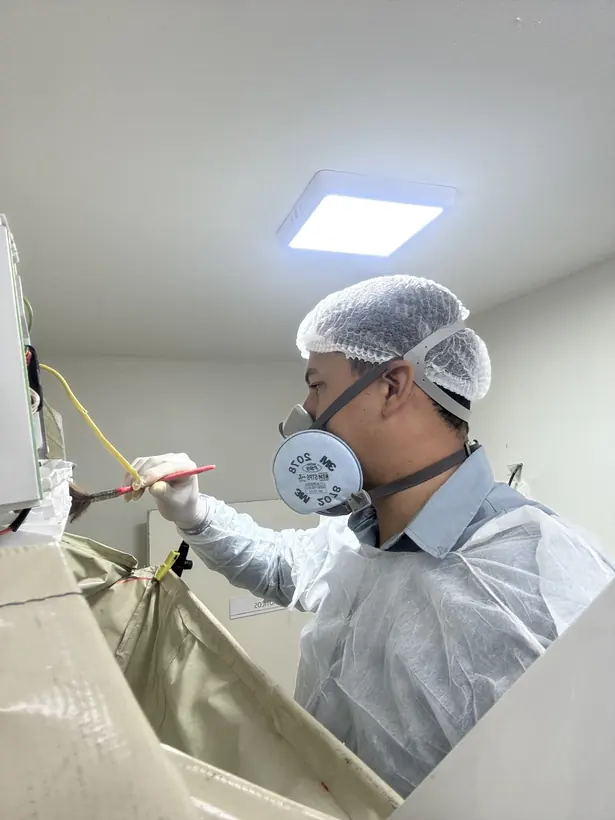 Técnico com touca e máscara realizando higienização de ar-condicionado