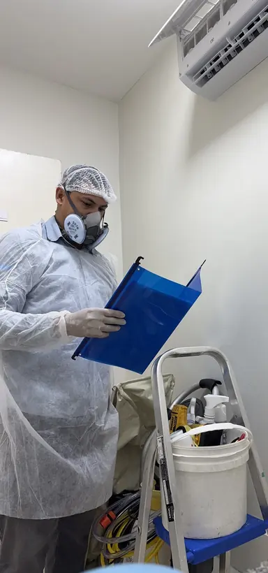 Técnico com equipamento de proteção registrando o atendimento em prancheta